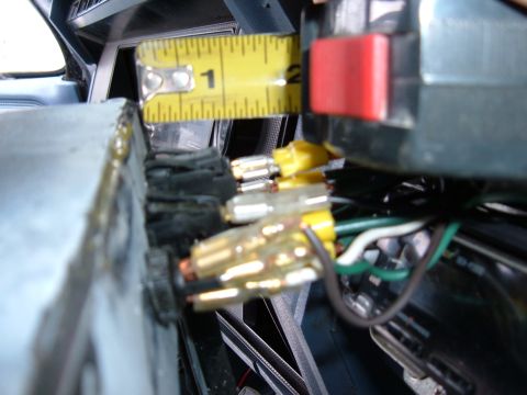 1985 Ford F-150 - A yellow measuring tape is positioned over a vehicle's interior wiring harness and dashboard components.
