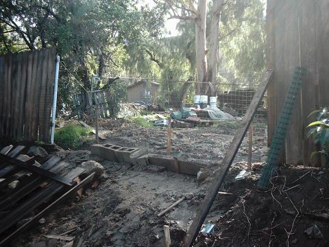 1978 Ford Bronco - Outdoor construction area with various building materials and overgrown vegetation.