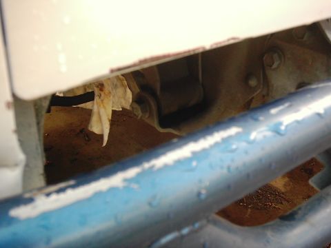 1978 Ford Bronco - A close-up view of a vehicle's undercarriage reveals blue bars and a white panel, with rags visible inside.