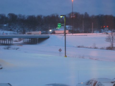 1985 Ford LTD Crown Victoria - A winter scene on a highway shows trucks on an overpass and cars covered in snow.