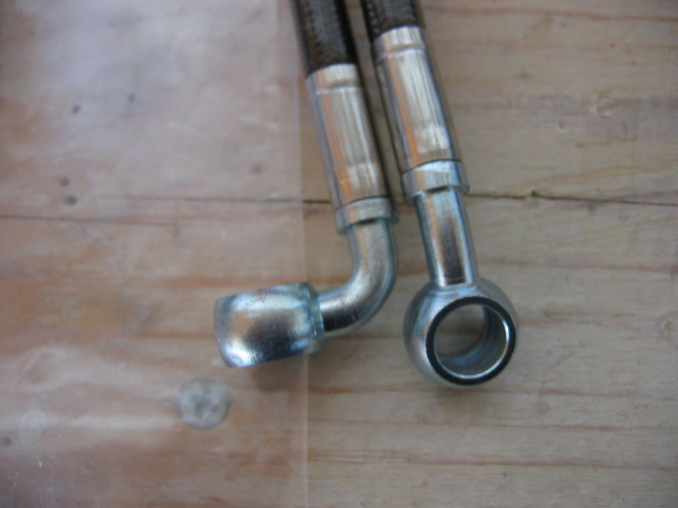 Close-up of two braided brake lines with metal fittings