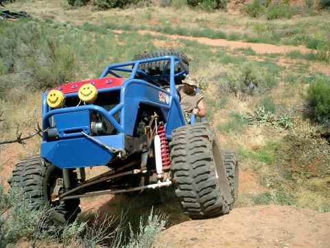 1979 Ford Bronco - Custom off-road buggy with smiley face headlights navigates a rocky, dusty trail.