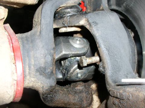 1978 Ford Bronco - Tight underbody shot of a solid front axle's inner CV/U-joint at the knuckle, with the greasy black axle housing, bearing caps and a bolt h…