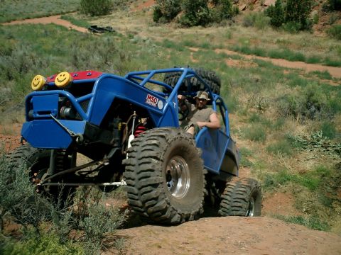 1979 Ford Bronco - A heavily modified off-road buggy navigates a dusty trail with its occupants.