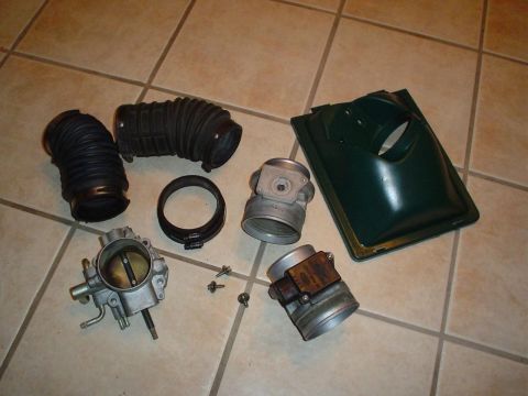 1993 Ford Taurus - Various car engine intake components are laid out on a tiled surface.