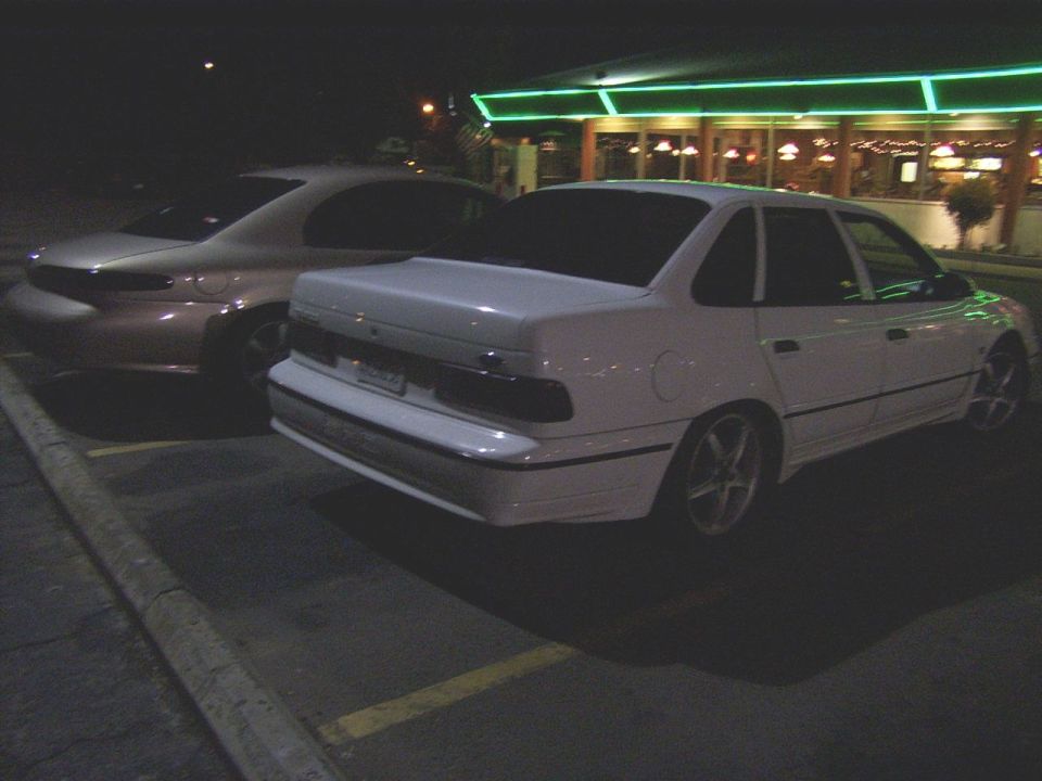 White 1995 Ford Taurus sedan, rear view, parked at night