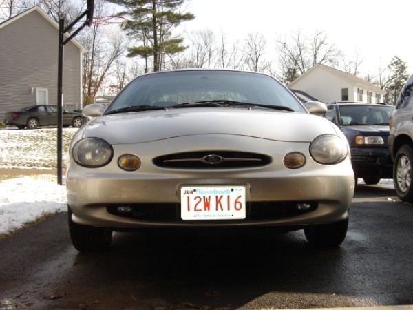 Silver Ford Taurus front view in driveway, Massachusetts plate 12WK16, snow patches on ground