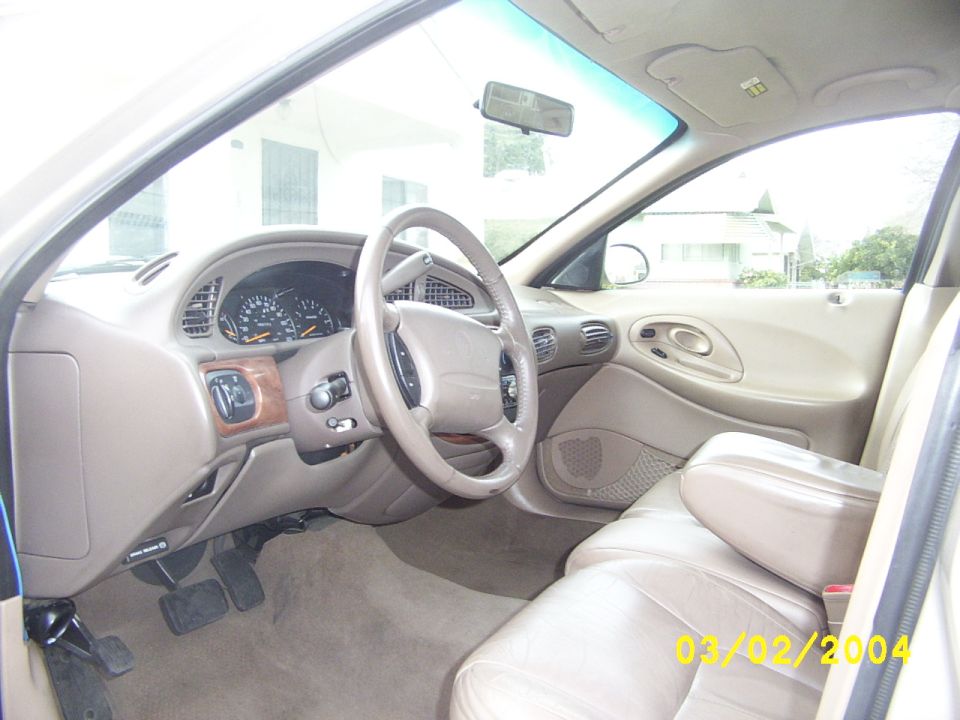 car interior with tan seats, steering wheel, and dashboard with gauges. Watermark says 03/09/2004