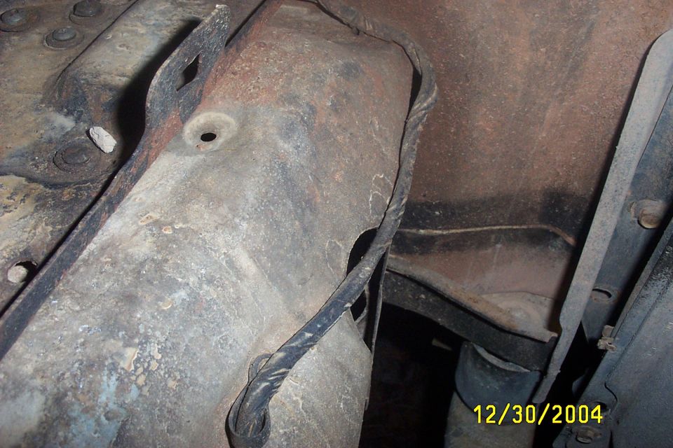 Close-up of rusted metal frame and wiring, likely from a vehicle's undercarriage
