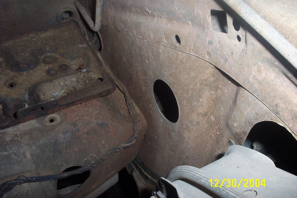 close-up of rusty vehicle frame and engine bay with a date stamp of 12/30/2004