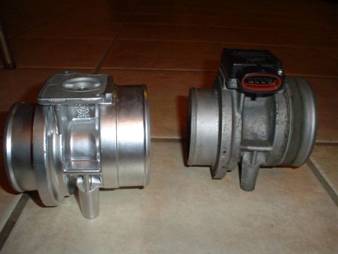 1993 Ford Taurus - Two mass airflow sensors are shown side-by-side on a tiled surface.
