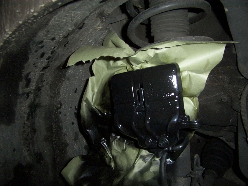 close-up of a black brake caliper covered in masking paper