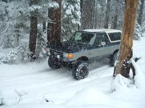 1989 Ford Bronco - A two-tone Ford Bronco navigates a snowy forest road during a winter outing.