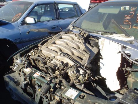 1993 Ford Taurus - Engine compartment of a car, with another vehicle in the background.