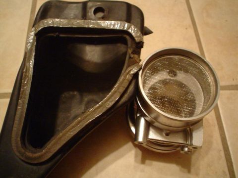 1993 Ford Taurus - Close-up of an air intake component, possibly a mass airflow sensor housing, with a fine mesh screen.