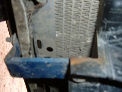 1985 Ford F-150 - Radiator and blue bracket detail, likely from the front of a vehicle.