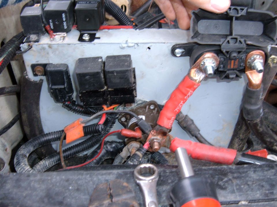 Inner-fender relay and mega-fuse panel with heavy red battery cables and copper lugs
