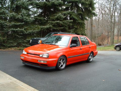 1994 Volkswagen Jetta - This orange 1994 Volkswagen Jetta sedan is shown from a 3q-front angle, parked on an asphalt driveway.