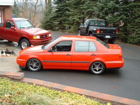 1994 Volkswagen Jetta - This orange 1994 Volkswagen Jetta sedan is shown in a side profile, a lowered stance and custom wheels.