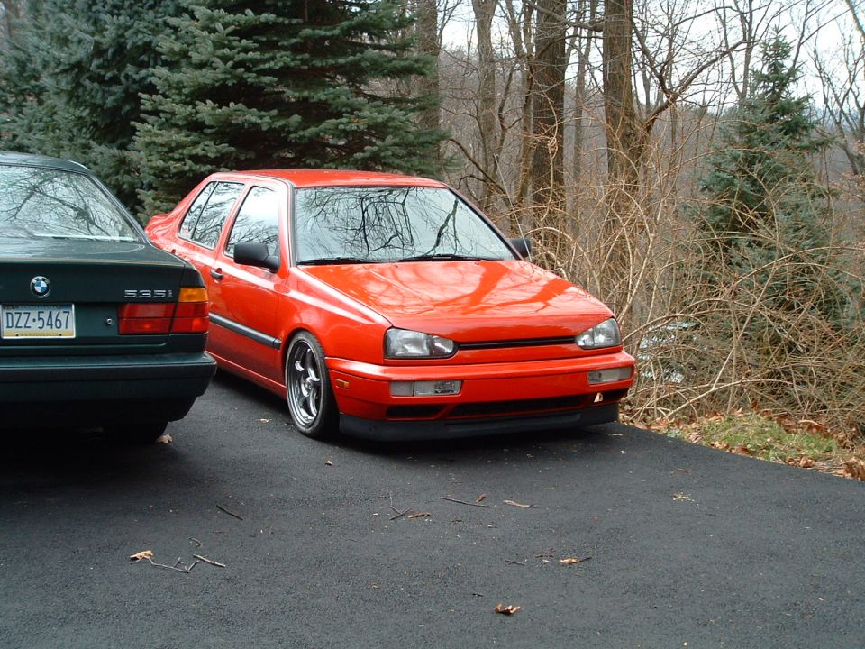 Lowered red VW Golf Mk3 hatchback on driveway beside green BMW 535i, front three-quarter view