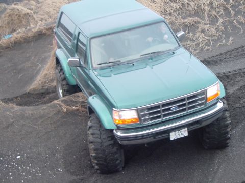 1996 Ford Bronco - 1996 Ford Bronco navigating rough terrain with its distinctive grille visible.