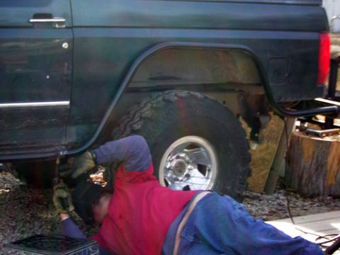 1995 Ford Bronco - A person works on the side of a 1995 Ford Bronco, focusing on the rear fender area.