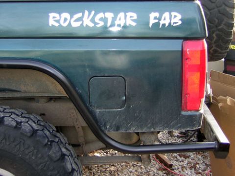 1995 Ford Bronco - Close-up of a green Ford Bronco's rear, showing a custom bumper and a 'ROCKSTAR FAB' decal.
