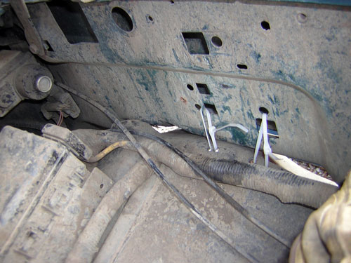 Brake and fuel lines zip-tied along a grimy teal inner fender and frame rail