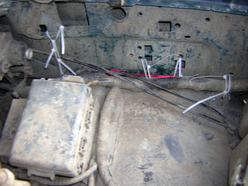Added wiring zip-tied along a dusty engine bay firewall and inner fender