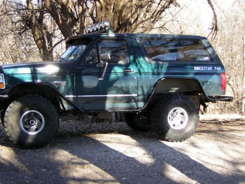 1995 Ford Bronco - Modified 1995 Ford Bronco with off-road lights and large tires is parked outdoors.