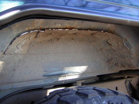 1995 Ford Bronco - Close-up of a vehicle's rusty wheel well, showing signs of modification and wear.
