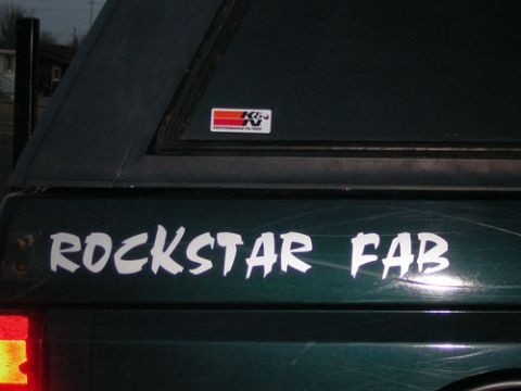 1995 Ford Bronco - A dark green truck bed with a camper shell displays a "ROCKSTAR FAB" decal and a K&N sticker.