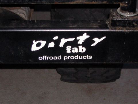 1995 Ford Bronco - Close-up of a black bumper a 'dirty fab offroad products' sticker, with a tire visible below.