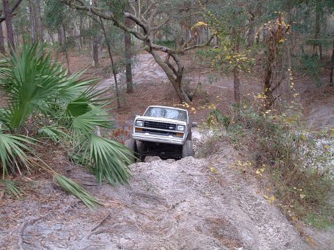 1995 Ford Bronco - This white SUV, likely from the early 1980s, navigates a challenging off-road course.