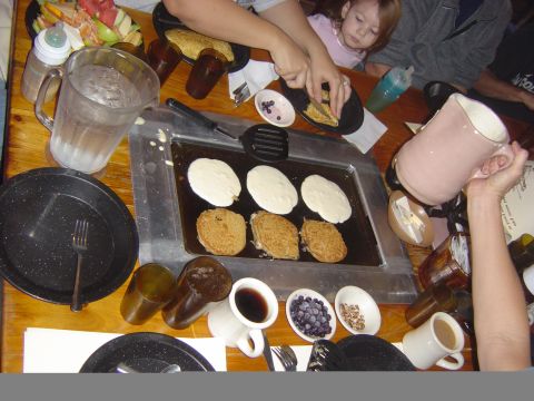 1993 Ford Bronco - A family enjoys a meal together, cooking pancakes on a griddle at a wooden table.
