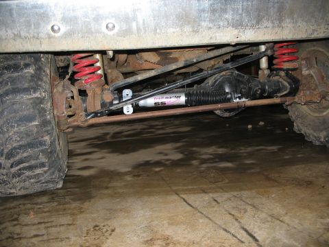 1988 Ford F-150 - Close-up view of the suspension components, including red springs and a Trail Master SS shock absorber, on a vehicle's undercarriage.