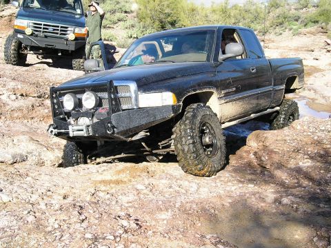 1993 Ford Bronco - Two off-road vehicles tackle a challenging rocky trail in a desert environment.
