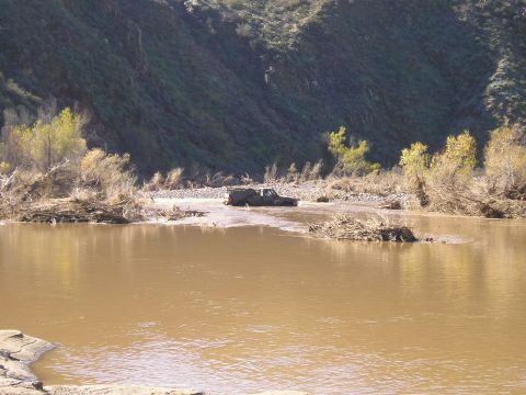 1993 Ford Bronco - A vehicle navigates a flooded area with debris and vegetation lining the banks.