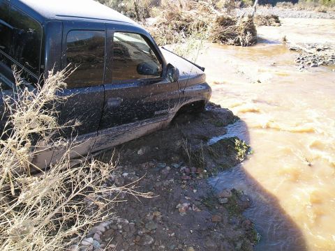 1993 Ford Bronco - Pickup truck is stuck in mud and water, with debris in the background.