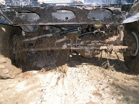 1993 Ford Bronco - The vehicle's undercarriage is caked in mud, with suspension components and tires partially submerged.