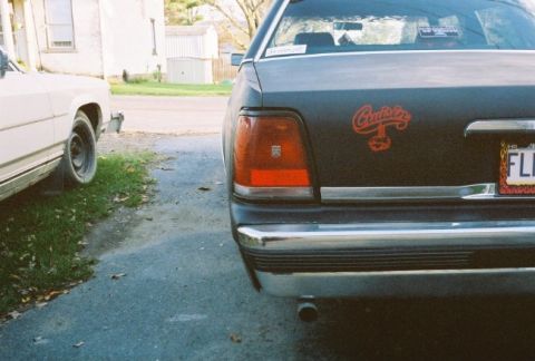 1989 Ford Crown Victoria LTD - The rear of a 1989 Ford Crown Victoria LTD, a 'Cruisers' decal and a license plate, parked next to another vehicle.
