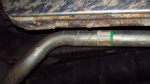 1985 Ford Crown Victoria LTD - Close-up of a rusted car undercarriage section and exhaust pipe with a part number visible.