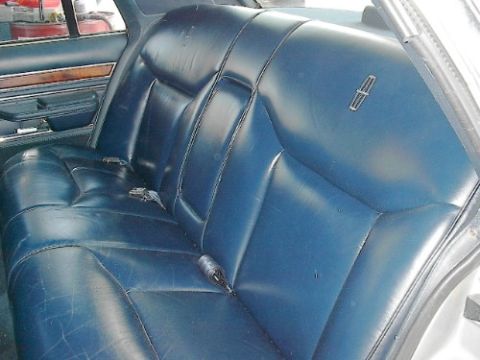 1989 Ford Crown Victoria LTD - The interior of a Lincoln Continental features a blue leather bench seat with a prominent Lincoln emblem.