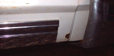 1985 Ford Crown Victoria LTD - Close-up of a white car's lower door panel showing mud and a small rust patch.