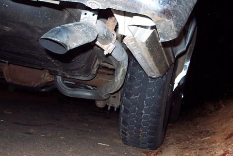 1985 Ford Crown Victoria LTD - Close-up view of the rear exhaust pipe and tire of a vehicle.