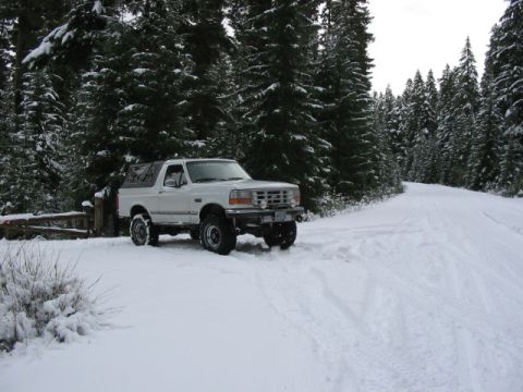 1995 Ford Bronco - 1995 Ford Bronco parked on a snowy forest road.
