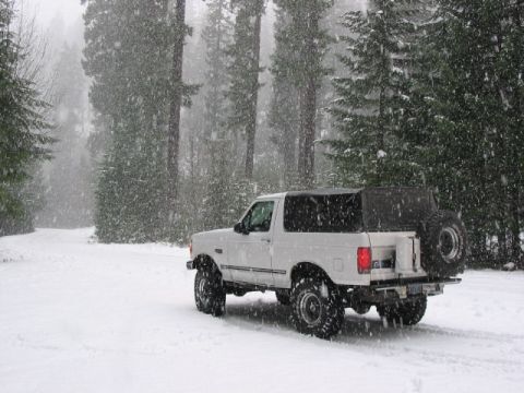 1995 Ford Bronco - White 1995 Ford Bronco navigates a snowy forest road during a snowfall.