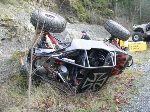 1978 Ford Bronco - An off-road buggy has overturned on its side next to a rocky embankment.