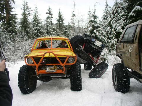 1978 Ford Bronco - Three-quarter front view of a chopped yellow Ford truck-based rock buggy with a full orange exterior roll cage, exposed winch and tube fron…