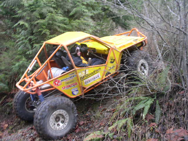 Yellow rock crawler with orange cage and BFGoodrich decals climbing a steep hillside